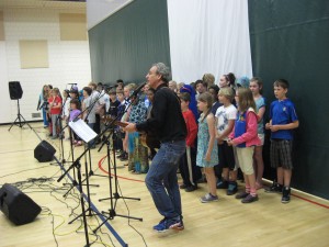 Folk artist Larry Long leads the gathering in song inspired by students at several schools participating May 30.