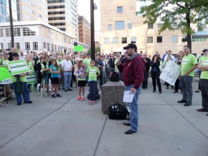 Tony Hair, President American Federation of Musicians, speaks at Rally for Minnesota Orchestra Musicians Oct 1, 2013.  At right, Tony Ross holds a sign held when the Lock-Out began one year earlier, October 1, 2012.
